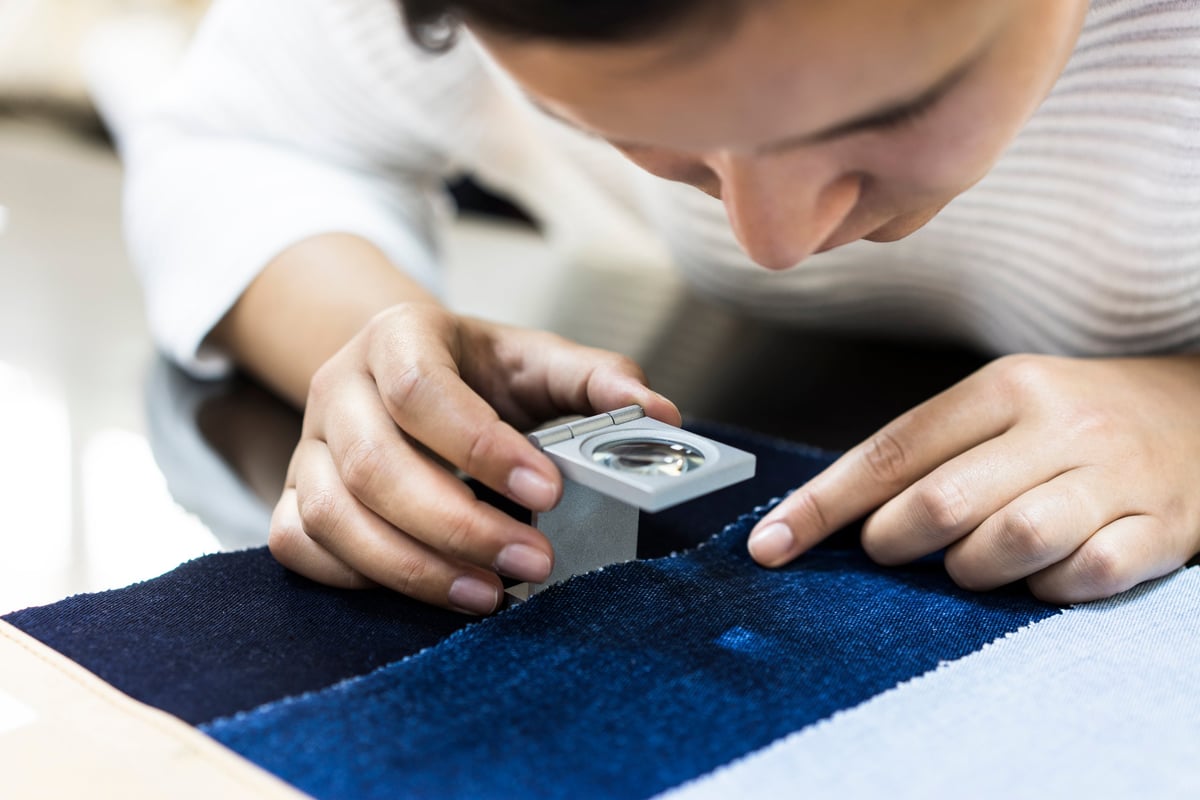 Mujer revisando calidad de tela con lupa