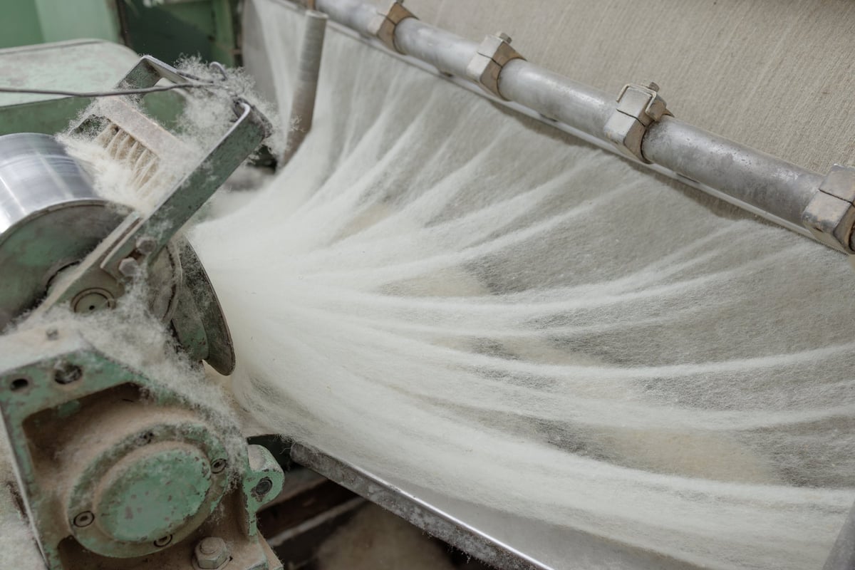 Producción textil industrial — cardado de lana en fábrica